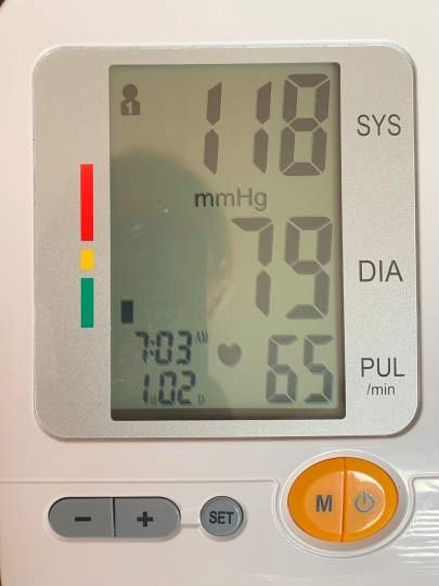 Digital home blood pressure monitor showing a reading of 118 systolic, 79 diastolic, and pulse 65 beats per minute.